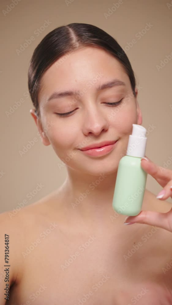 Portrait young woman uses creams of her face. Concept for fresh moisturized skin beautiful closeup cosmetic face happy healthy model. Model with a bottle of face cream. Slow motion, vertical video Portrait young woman uses creams of her face. Concept for fresh moisturized skin beautiful closeup cosmetic face happy healthy model. Model with a bottle of face cream. Slow motion, vertical video
