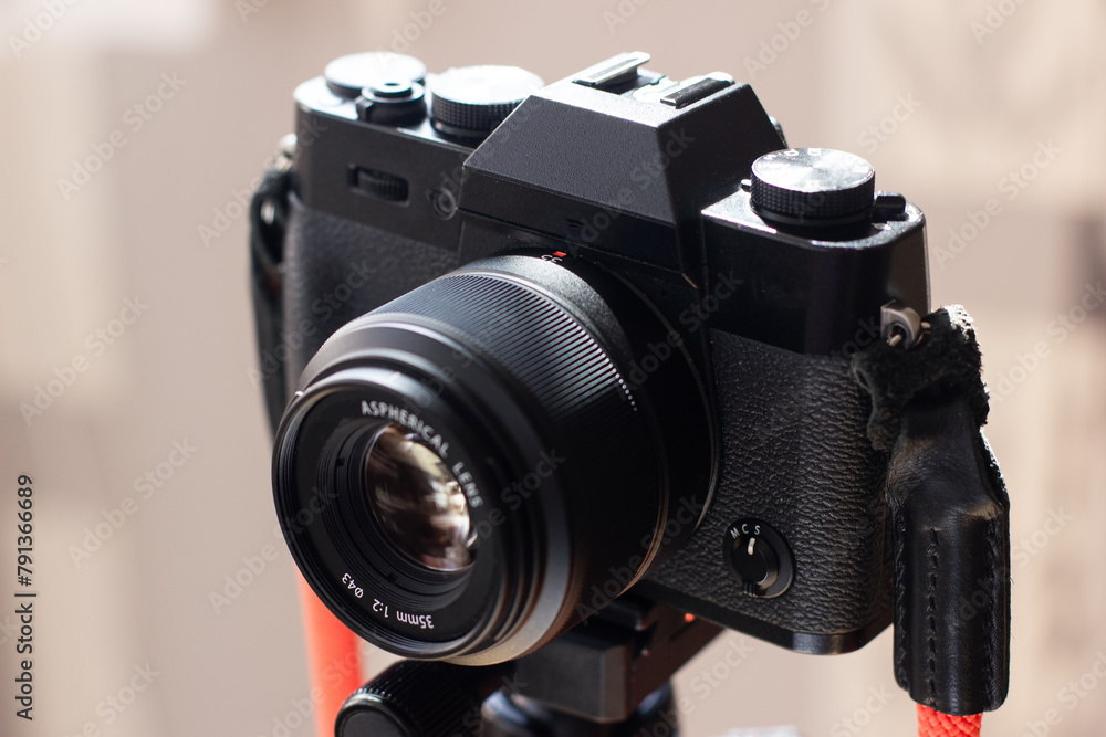 The black retro designed camera is mounted on a tripod for making photo or video footage.