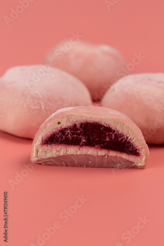 Traditional Japanese dessert, mochi cake in thin pink rice dough on a pink background with pink filling, cut, open space