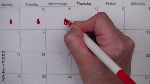 Hand draws red drops on the calendar, then places a red checkmark in a circle - concept of menstrual cycle tracking, ovulation, and pregnancy planning