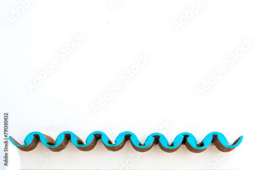 White concrete wall with blue turquoise waves formed by overlapping roof tiles. photo