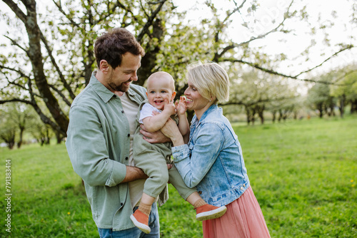 New parents holding small toddler, baby, outdoors in spring nature. Older First-time parents. © Halfpoint