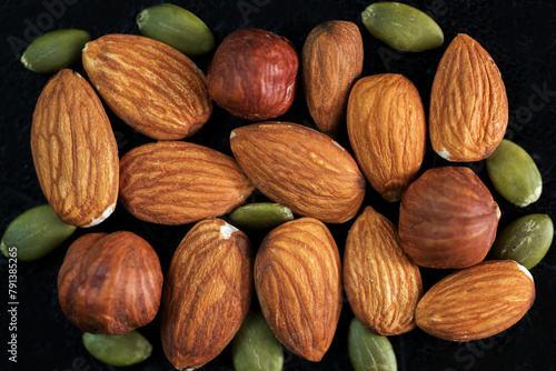 different nuts healthy snack background of almonds, hazelnuts, pumpkin seeds on dark