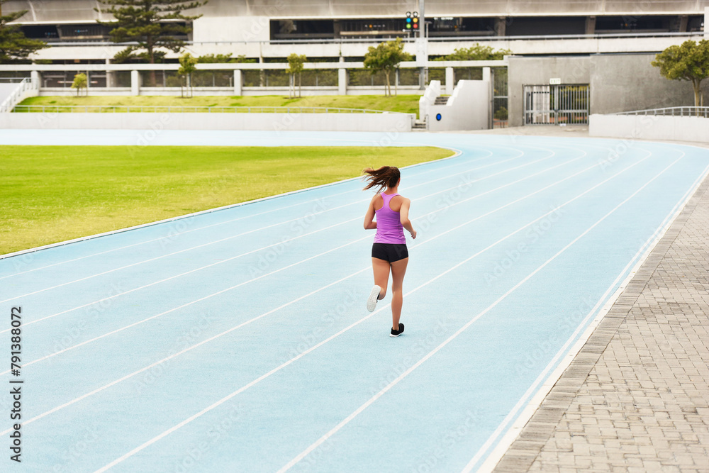 Fototapeta premium Back, woman and running on race track for athletics, fitness or competition training in stadium. Runner, exercise and female person for sports performance, endurance challenge or cardio workout