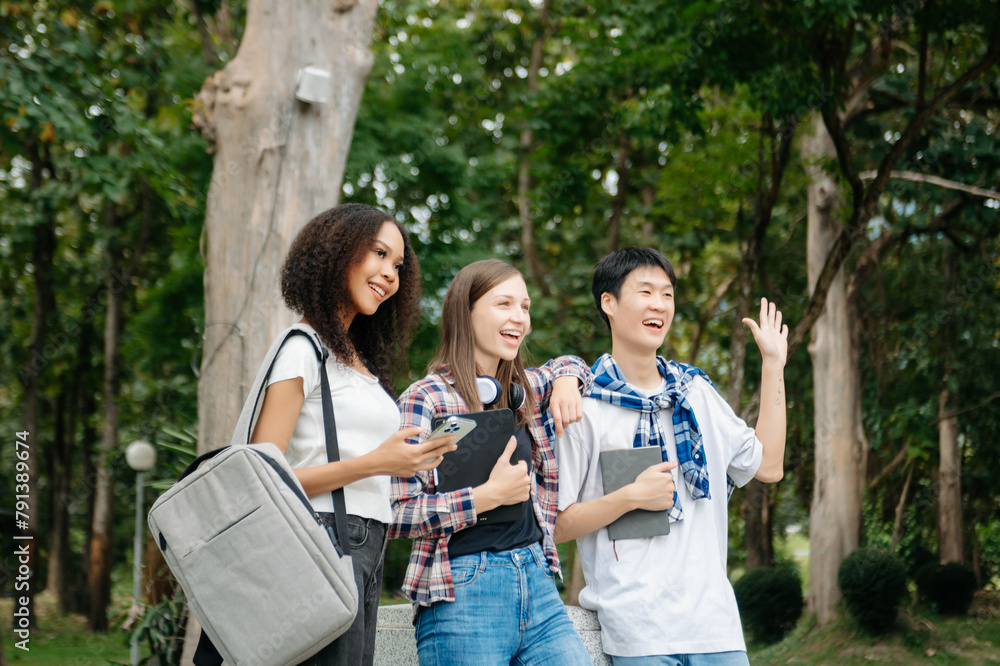 Three young college students is reading a book while relaxing sitting on grass in a campus park with her friends. Three young college students is reading a book while relaxing sitting on grass in a campus park with her friends.