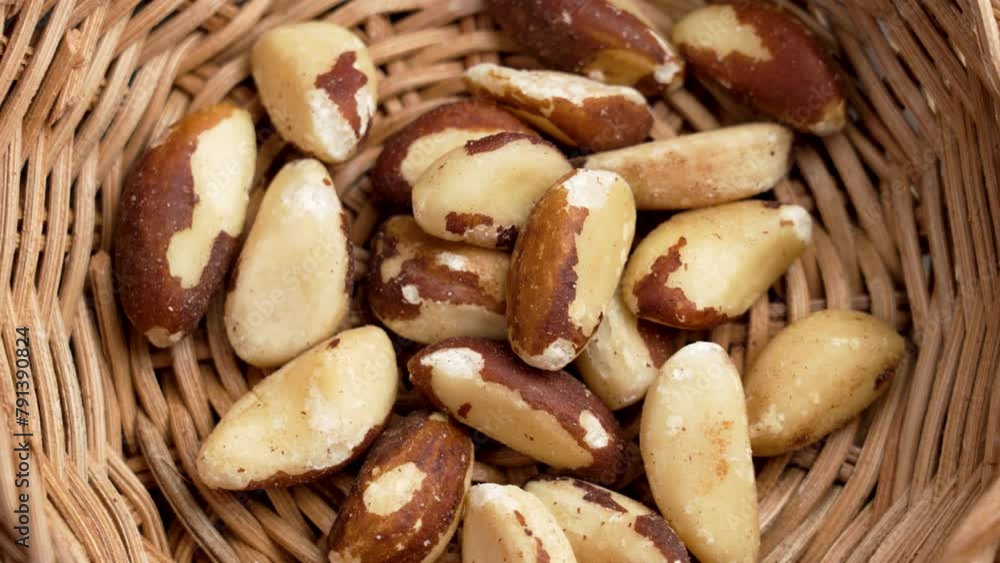 Organic dried Brazil nuts in rustic rattan bowl close up. Tasty nutty snack. Nutritional source of selenium nutrient. Top view. Rotation Organic dried Brazil nuts in rustic rattan bowl close up. Tasty nutty snack. Nutritional source of selenium nutrient. Top view. Rotation