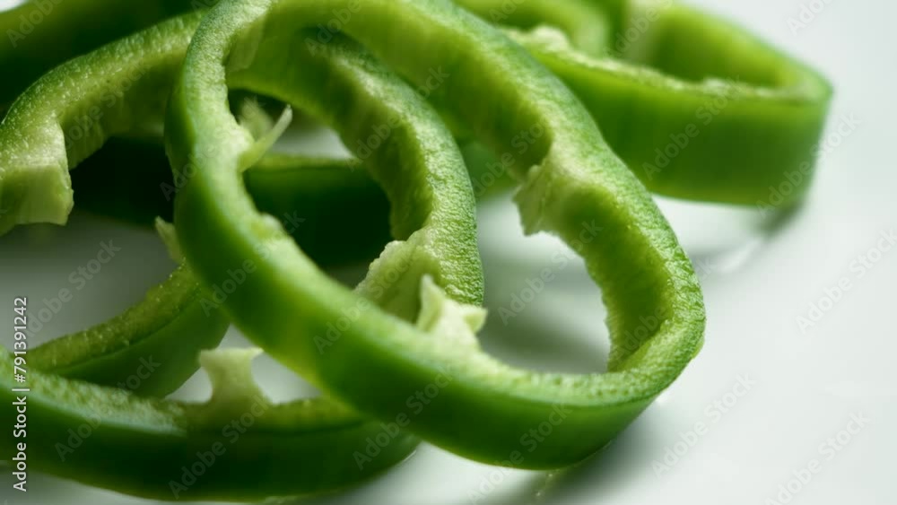 Sliced organic green bell peppers on a white ceramic plate close up. Rotation Sliced organic green bell peppers on a white ceramic plate close up. Rotation