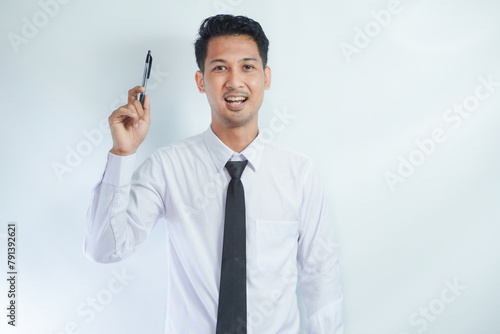Young Asian businessman smiling and pointing finger up while holding a book photo