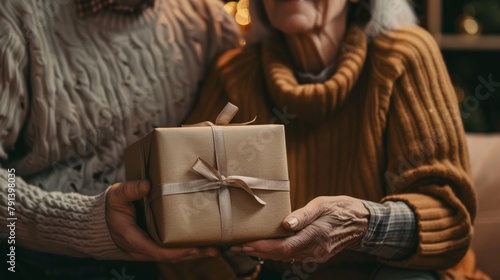 Close-up of a young man presenting a beautifully wrapped, elegant gift to his mother, tender moment, soft lighting