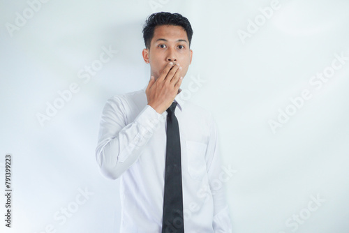 Headshot of terrified fearful young Asian businessman covering mouth and looking at camera with scared expression on his face, afraid of being fired failure at work