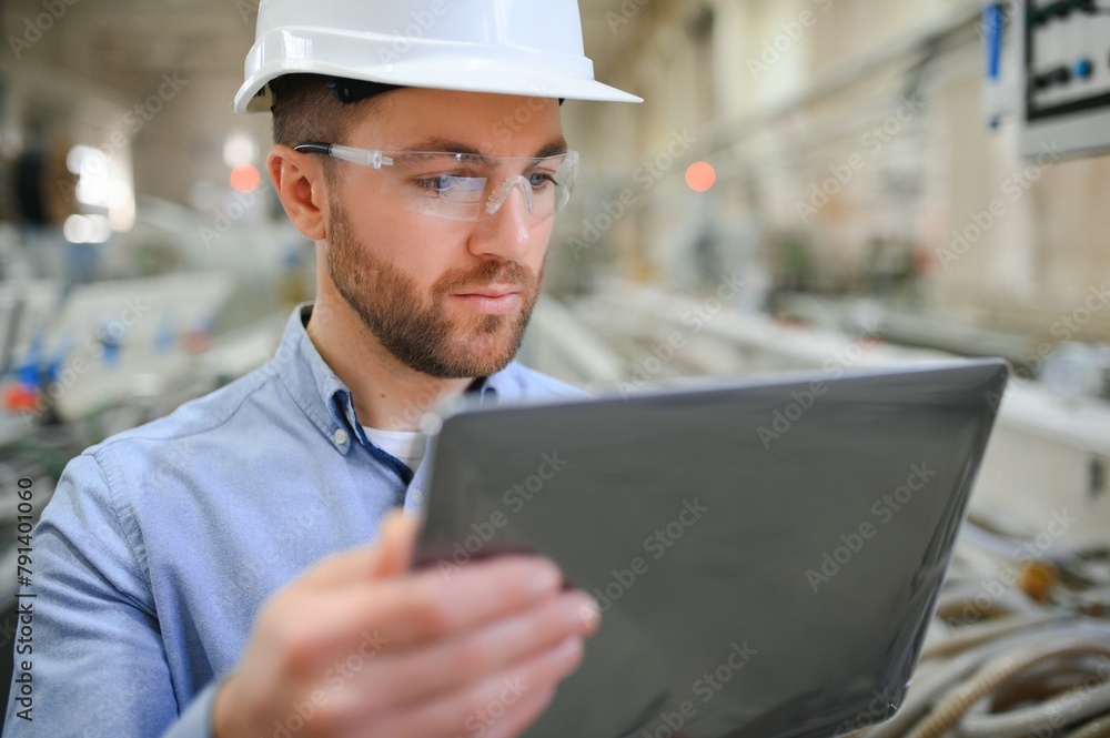 Engineer in hardhat is using a laptop in a heavy industry factory Engineer in hardhat is using a laptop in a heavy industry factory