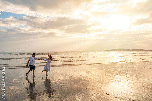 Young woman traveler holding man's hand and looking beautiful sunset on the beach, Couple on vacation in summer concept