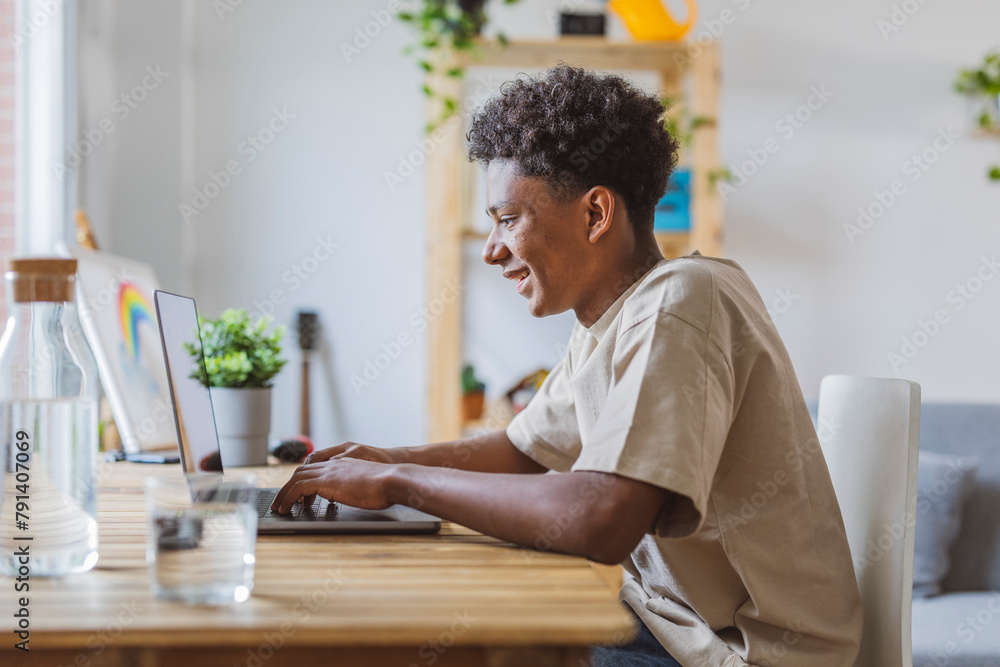 Smiling teenage boy using laptop at home Smiling teenage boy using laptop at home
