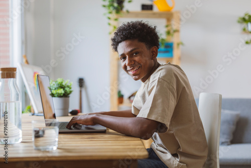 Happy teenage boy using laptop at home photo