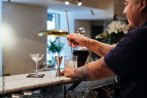 Smiling bartender stirring cocktail with spoon at restaurant photo