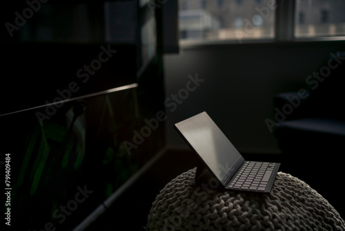 Tablet PC with keyboard kept on hassock in dark office photo