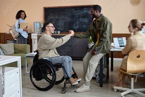 Happy businessman with disability shaking hands with colleague in office photo
