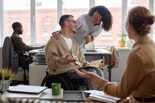 Happy business people congratulating colleague with disability for getting promotion in office photo