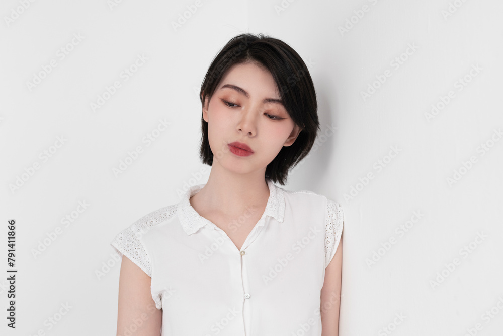 Thoughtful woman in white dress leaning on white backdrop Thoughtful woman in white dress leaning on white backdrop