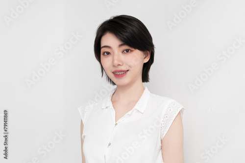 Smiling young woman with dental braces against white background photo