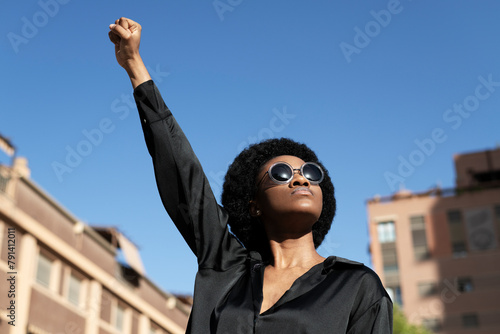 Rebel Afro woman holding fist under blue sky photo