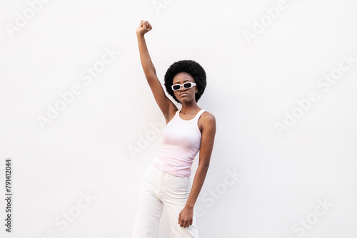 Young woman wearing sunglasses and protesting against white background photo