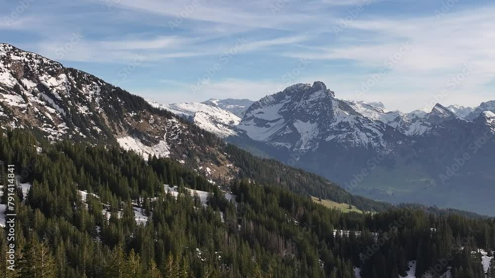 Stunning drone shot of Amden Arvenbuel, Switzerland, showing majestic snow-capped mountain ranges and picturesque canopies of alpine trees with blue skies and white clouds in a winter day Stunning drone shot of Amden Arvenbuel, Switzerland, showing majestic snow-capped mountain ranges and picturesque canopies of alpine trees with blue skies and white clouds in a winter day