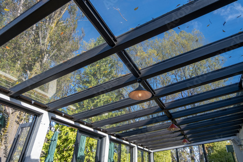 Schilderij op canvas A glass roof of a sunroom creates a light and airy ambiance, allowing natural light to filter through the transparent ceiling, the large windows offer a view of the green trees