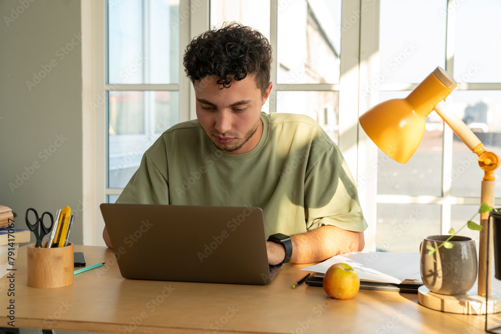 Freelancer using laptop at desk in home office Freelancer using laptop at desk in home office