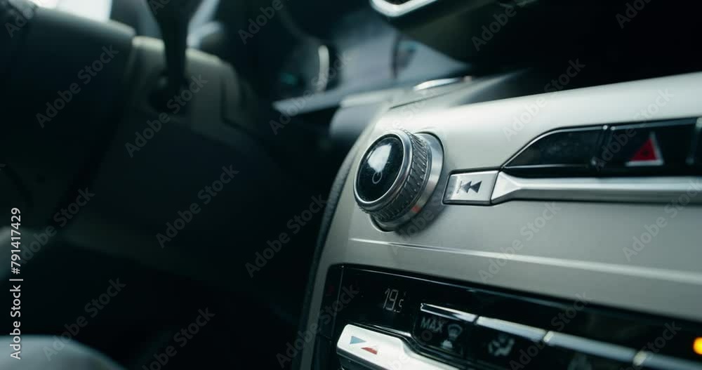 A woman's hand turns the volume control lever in the car's audio player while driving, an unrecognizable person A woman's hand turns the volume control lever in the car's audio player while driving, an unrecognizable person