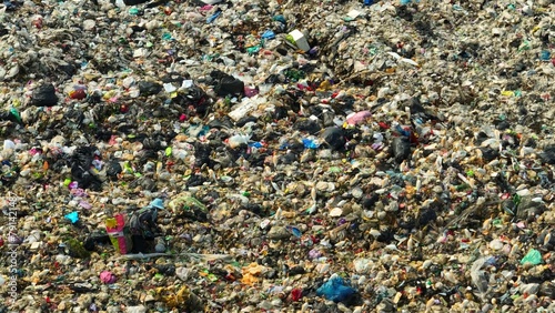 A drone surveys a sea of trash, a mosaic of hues and materials, sprawling across a vast landfill. Colors blend in chaos, revealing our society's discarded remnants in this waste disposal expanse. 