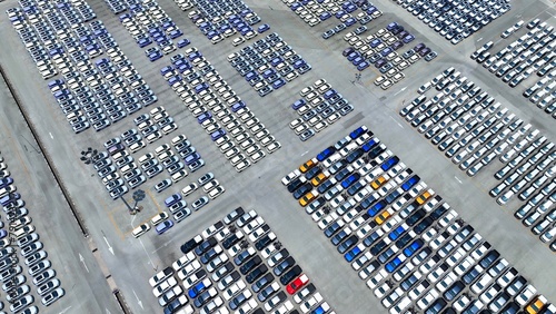 Fototapeta Naklejka Na Ścianę i Meble -  An expansive parking lot sprawls below, a sea of neatly aligned cars gleaming under the sunlight, a testament to orderliness and efficiency in the realm of automotive management.
