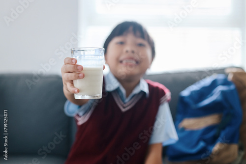 Healthy schoolboy in uniform drinking glass of milk for breakfast before go to school. photo