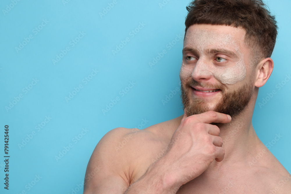 Fototapeta premium Handsome man with facial mask on his face against light blue background, space for text
