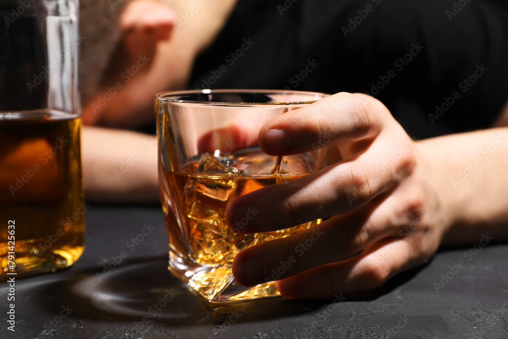 Alcohol addiction. Man with glass of whiskey at dark textured table, selective focus Alcohol addiction. Man with glass of whiskey at dark textured table, selective focus