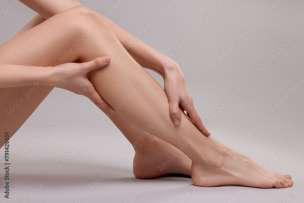 Woman suffering from leg pain on grey background, closeup Woman suffering from leg pain on grey background, closeup