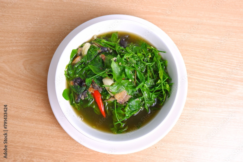 Melientha suavis soup with grilled catfish in a white bowl on a brown wooden table. Thai food Melientha suavis soup with grilled catfish in a white bowl on a brown wooden table. Thai food
