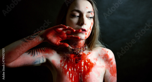 Portrait of young woman with red paint on her chest on dark background. © Vladimir Arndt