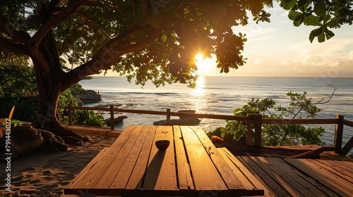 A terrace with a wooden table overlooking a beach landscape bathed in either sunset or sunrise light, featuring a silhouette of a tropical tree against a seascape, perfect for a summer vacation photo