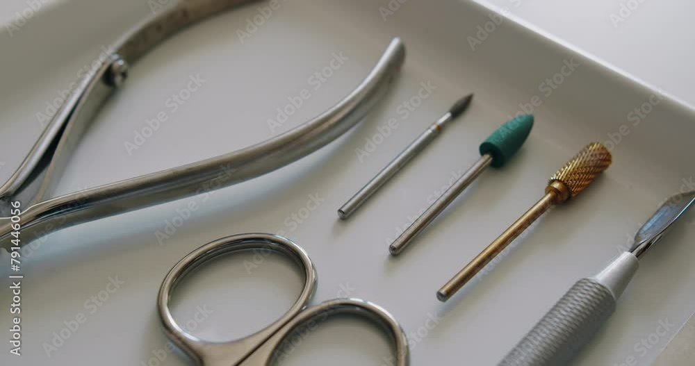 Cuticle stainless steel pusher, nippers, scissor and nozzles. Professional instruments for fingernail treatment. Professional manicure instruments on white table in beauty salon ready for use. Cuticle stainless steel pusher, nippers, scissor and nozzles. Professional instruments for fingernail treatment. Professional manicure instruments on white table in beauty salon ready for use.