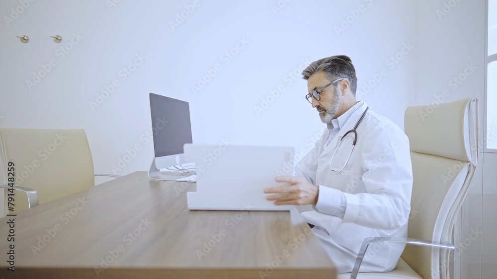 Caucasian Doctor examining documents on a tablet at desk. Caucasian Doctor examining documents on a tablet at desk.
