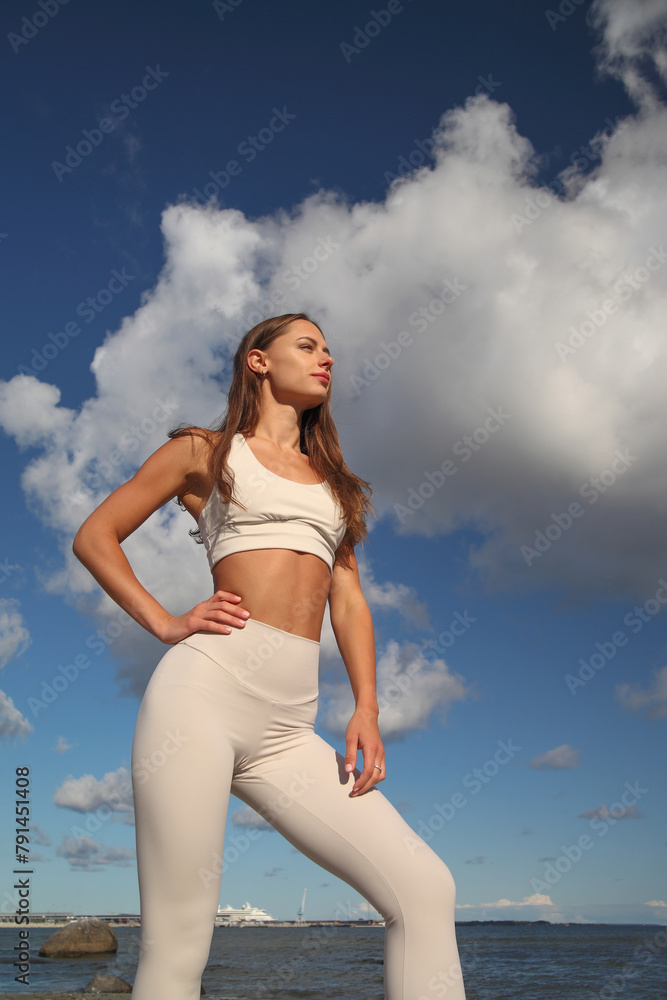 young athletic woman in white tracksuit by the sea