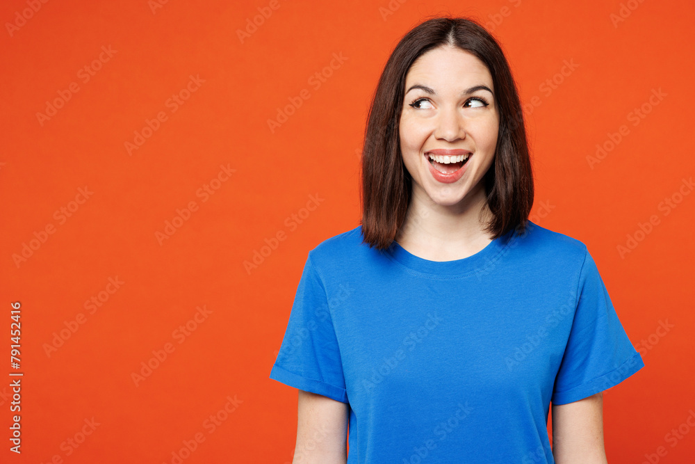 Young surprised shocked excited fun exultant woman she wear blue t-shirt casual clothes look aside on area mockup isolated on plain red orange color wall background studio portrait. Lifestyle concept. Young surprised shocked excited fun exultant woman she wear blue t-shirt casual clothes look aside on area mockup isolated on plain red orange color wall background studio portrait. Lifestyle concept.