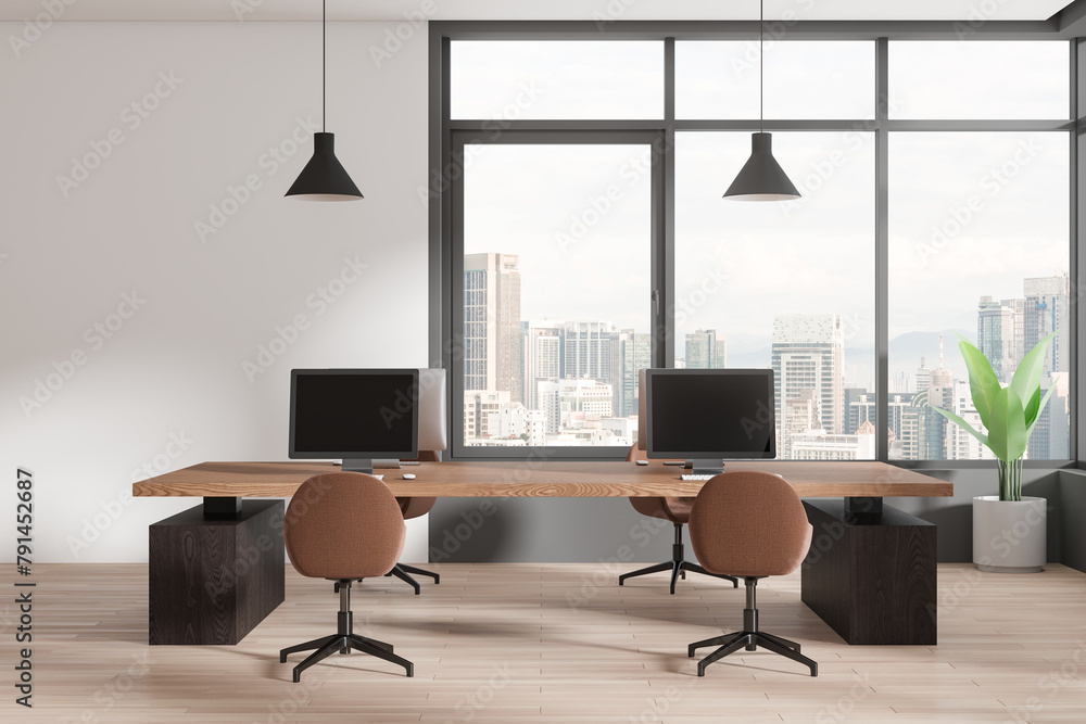 Fototapeta premium Modern coworking interior with pc computers on desks in row, panoramic window