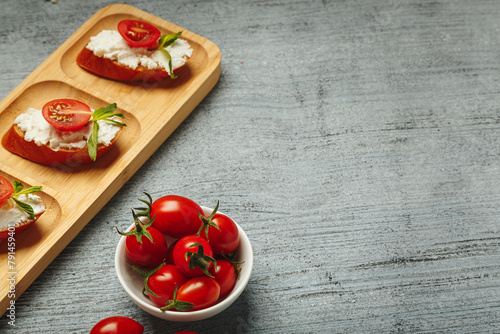 Healthy snack prepared from fresh baguette and cream cheese with tomato and greenery. Lunchtime recipe to cook at home