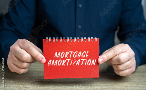 Mortgage amortization concept. Process of paying off a mortgage loan through regular payments over time. Real estate and loan. Notepad in the hands of man