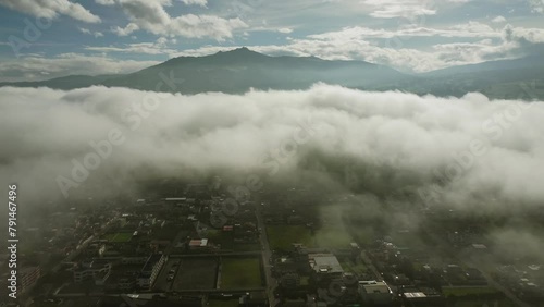 Aerial view over Machachi City with low condensation fog. In the distance, the silhouette of Pasochoa volcano. Breathtaking bird's eye view photo