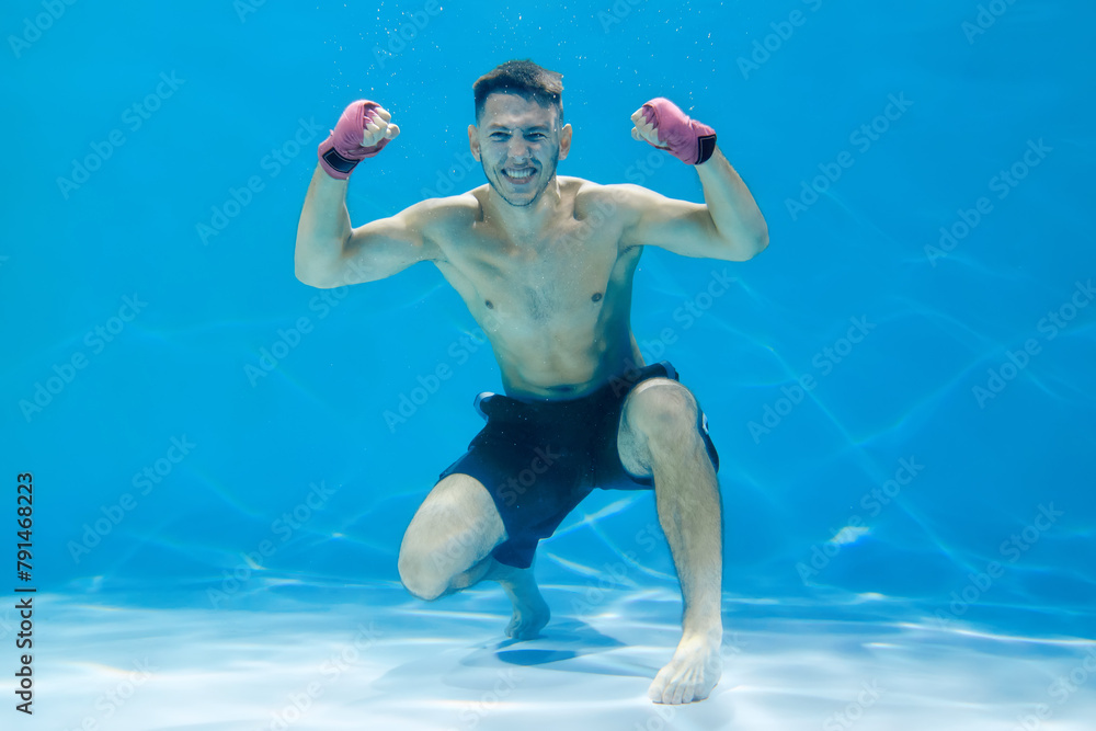 Angry athlete man with boxing gloves releasing energy while underwater