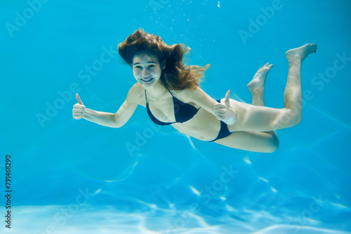 Cute young woman enjoying swimming in a clean pool