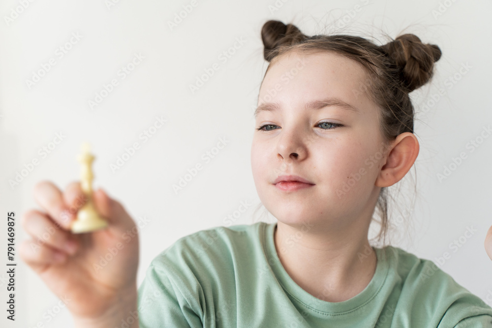 Little girl looking at the chess piece of the white king, holding it in her hands, with a sense of victory. Selected Focus Little girl looking at the chess piece of the white king, holding it in her hands, with a sense of victory. Selected Focus